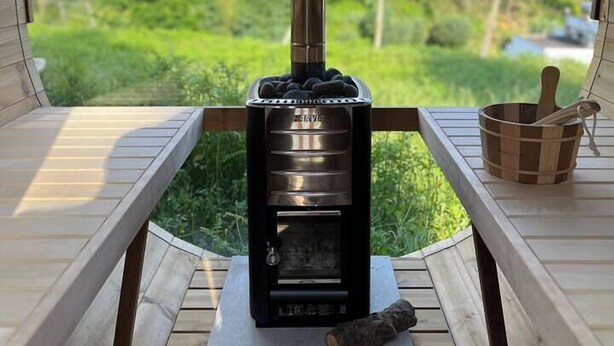 A wood-burning stove in a circular room with a view of a forested area. - Casa da Oliveira Pool Spa Wellness Retreat @Gerês (São Jorge)