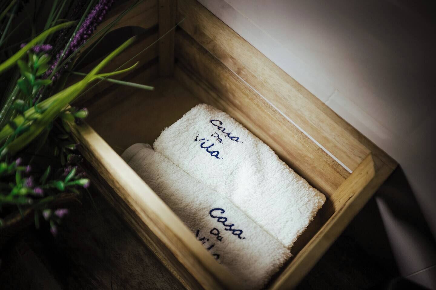 A wooden box containing a white towel with the text "Casa de la" and "Casa de la" repeated.