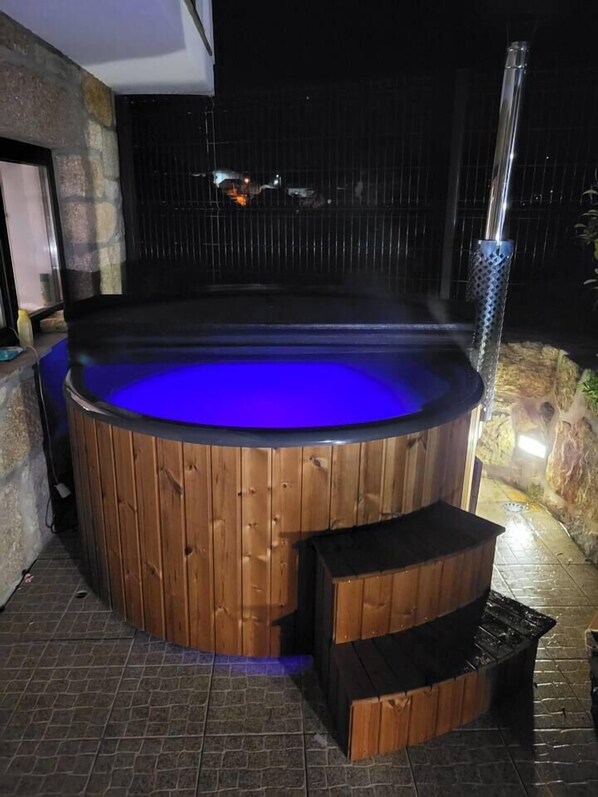 A hot tub with a wooden exterior and a blue light.
