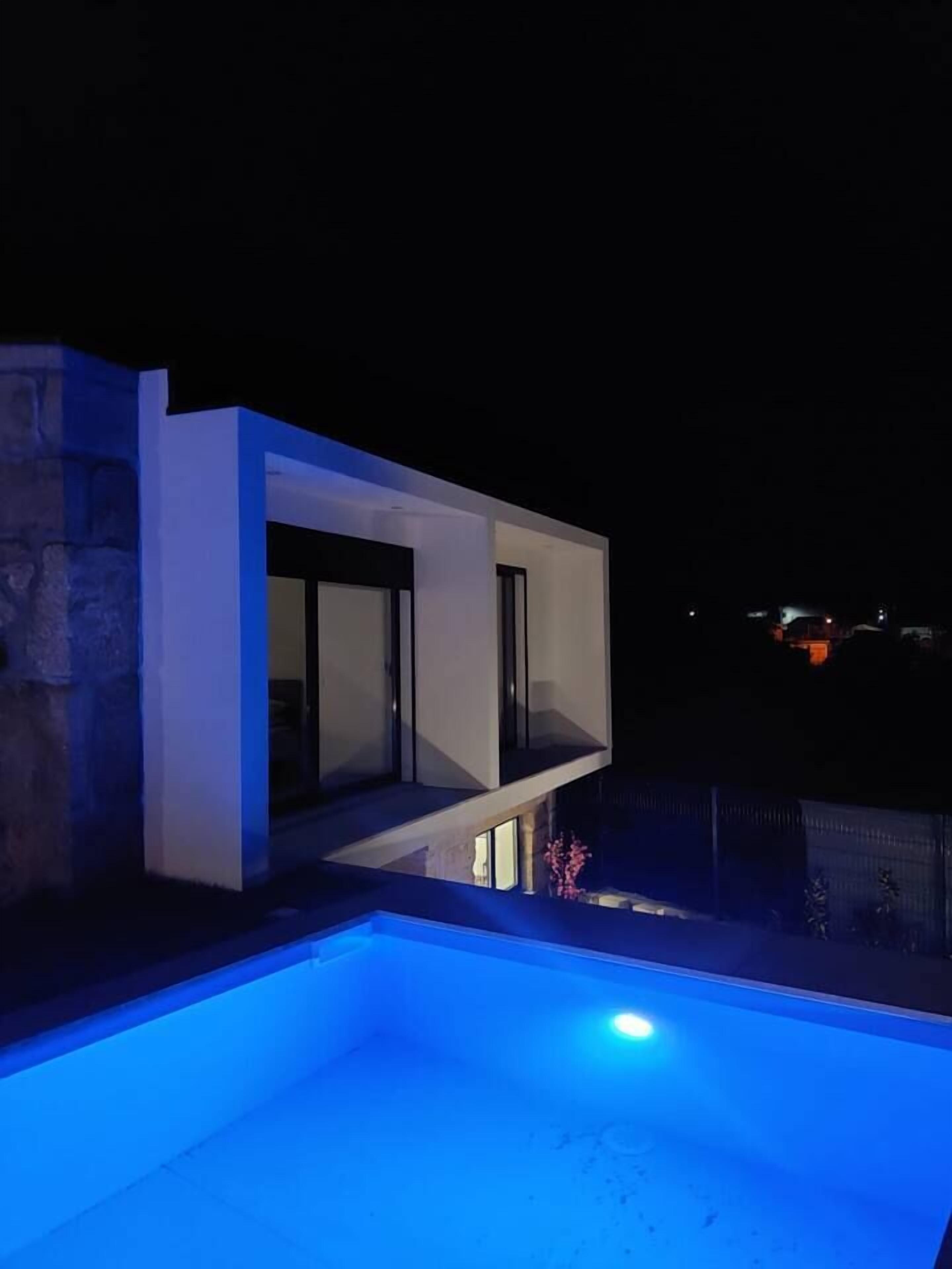 Ein modernes Haus mit Schwimmbad bei Nacht.