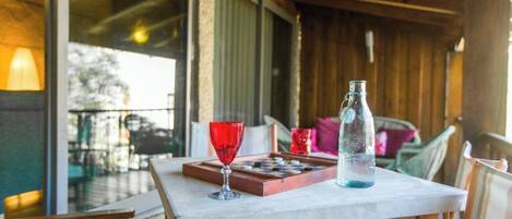 Una terraza de madera con una mesa preparada para dos personas, que incluye un vaso y una botella.