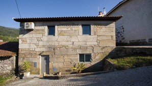 A stone building with a tiled roof, a small door, and two windows.
