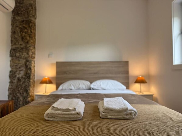 Una habitación de hotel con una cama, dos lámparas de noche y dos toallas dobladas sobre la cama.