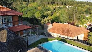 Zona de piscina con vistas despejadas del paisaje circundante, que incluye una casa con techo de tejas rojas y una construcción de piedra.