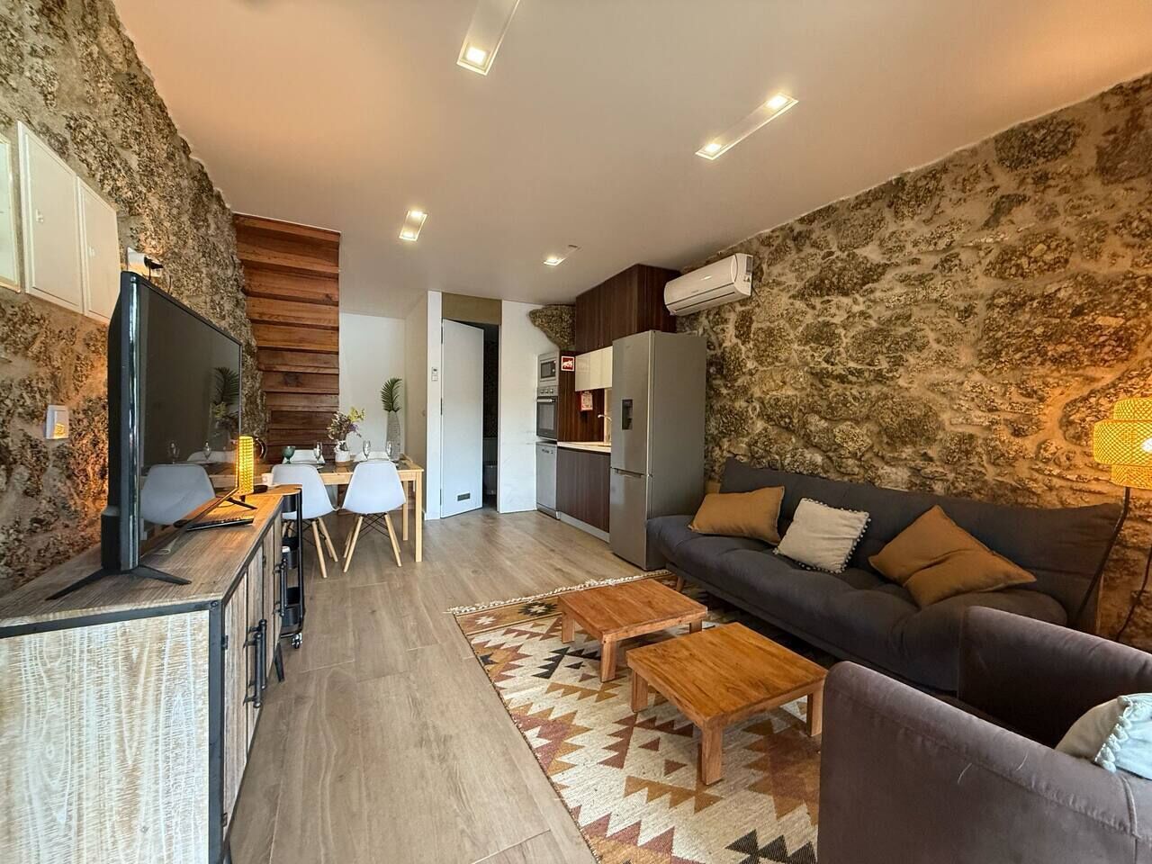 Ein modernes Wohnzimmer mit Steinwand, einer Couch, einem Couchtisch und einem Fernseher.