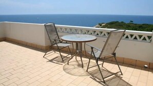 Une terrasse avec une table et des chaises, donnant sur la mer.