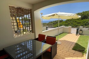 A balcony with a table and chairs, a view of the sea, and a white umbrella. - Apartment in the heart of Benagil (Benagil)