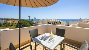 Una terraza con mesa, sillas y un gran paraguas.