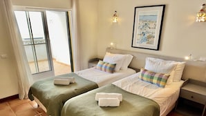 A hotel room with two beds, a balcony, and a framed picture on the wall. - Charming apartment near Atlantic Ocean (Benagil)