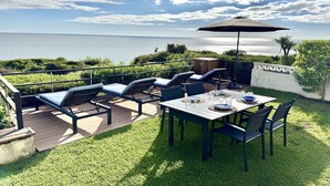 An outdoor patio with a table set for dining, lounge chairs, and a view of the sea. - Charming apartment near Atlantic Ocean (Benagil)