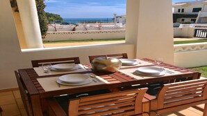 A dining table set for four with a view of the sea and buildings in the background. - Family-Friendly Villa in Benagil (Benagil)