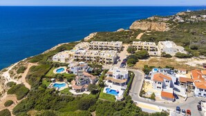 An aerial view of a coastal residential area with multiple buildings, a beach, and a lighthouse in the distance. - Holiday home near Praia de Benagil beach (Benagil)