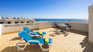 A rooftop terrace with blue lounge chairs and a table, overlooking the sea. - Holiday home near Praia de Benagil beach (Benagil)