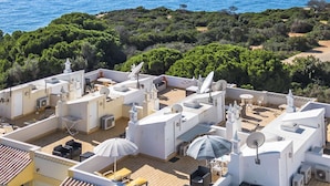 Una terraza en la azotea con múltiples antenas parabólicas, muebles de exterior y vista al mar.