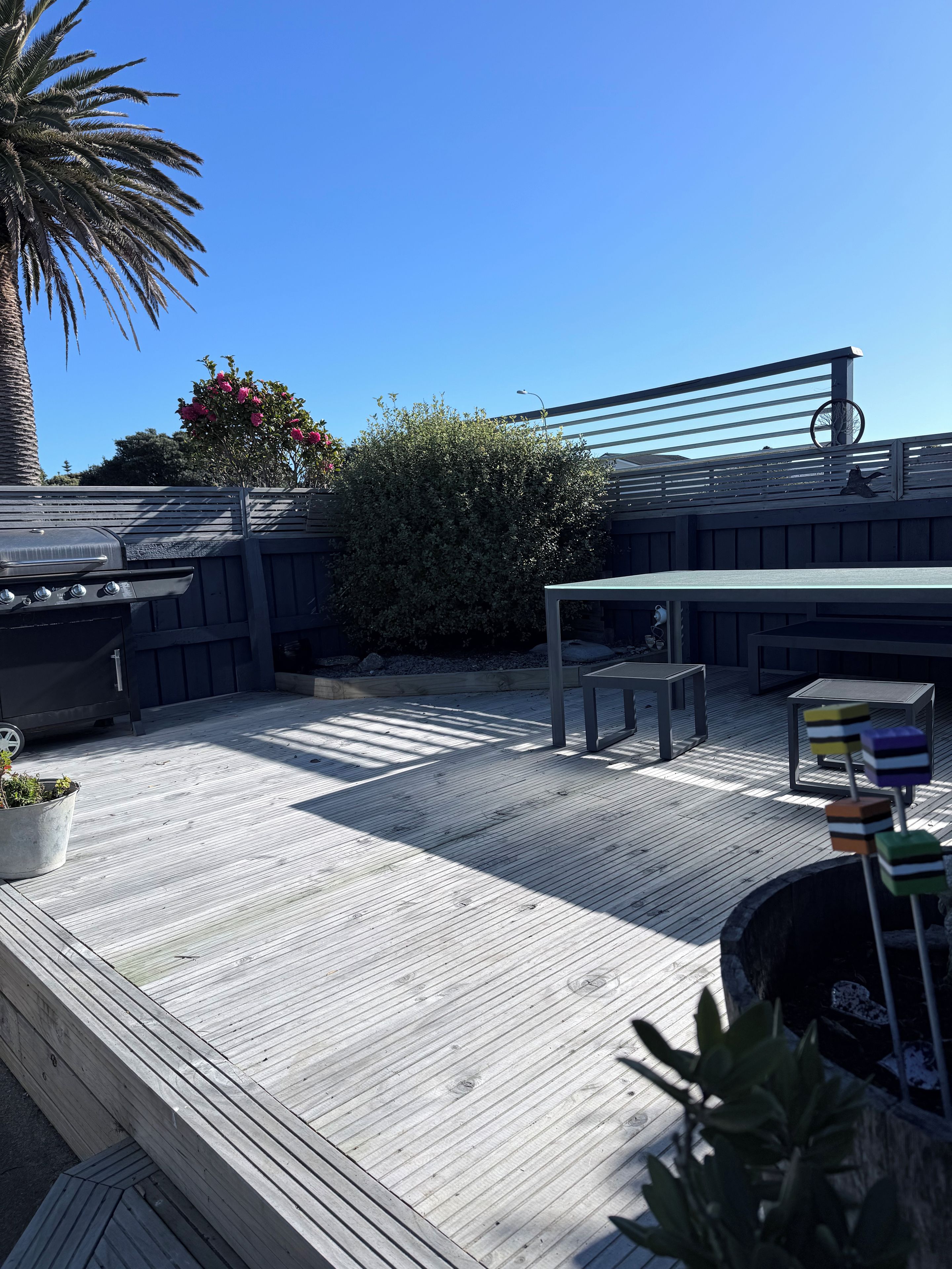 A wooden deck with a grill, seating, and potted plants.