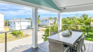 A covered outdoor patio with a table and chairs, overlooking a residential area with houses and greenery. - Brand New! Steps to Beach, Private Pool and Hot Tub, Putt-Putt, Fenced Yard, $300 in Free Tickets! (St. Augustine)
