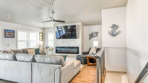 A spacious living room with a grey sofa, a flat-screen TV, a fireplace, and nautical-themed decor. - Brand New! Steps to Beach, Private Pool and Hot Tub, Putt-Putt, Fenced Yard, $300 in Free Tickets! (St. Augustine)
