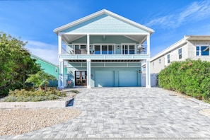 A two-story house with a covered front porch, a garage, and a landscaped driveway.