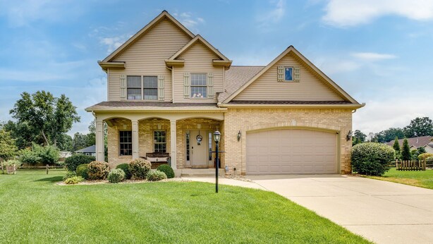 A two-story house with a front porch, a garage, and a well-maintained lawn.