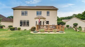 A two-story house with a front deck, a small garden, and a clear sky.