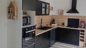Une cuisine moderne avec des meubles de rangement noirs et blancs, un plan de travail en bois et un four encastré.