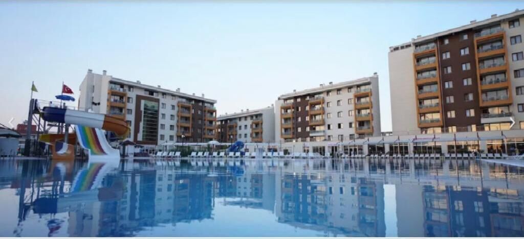 A hotel with a swimming pool, multiple balconies, and a water slide.