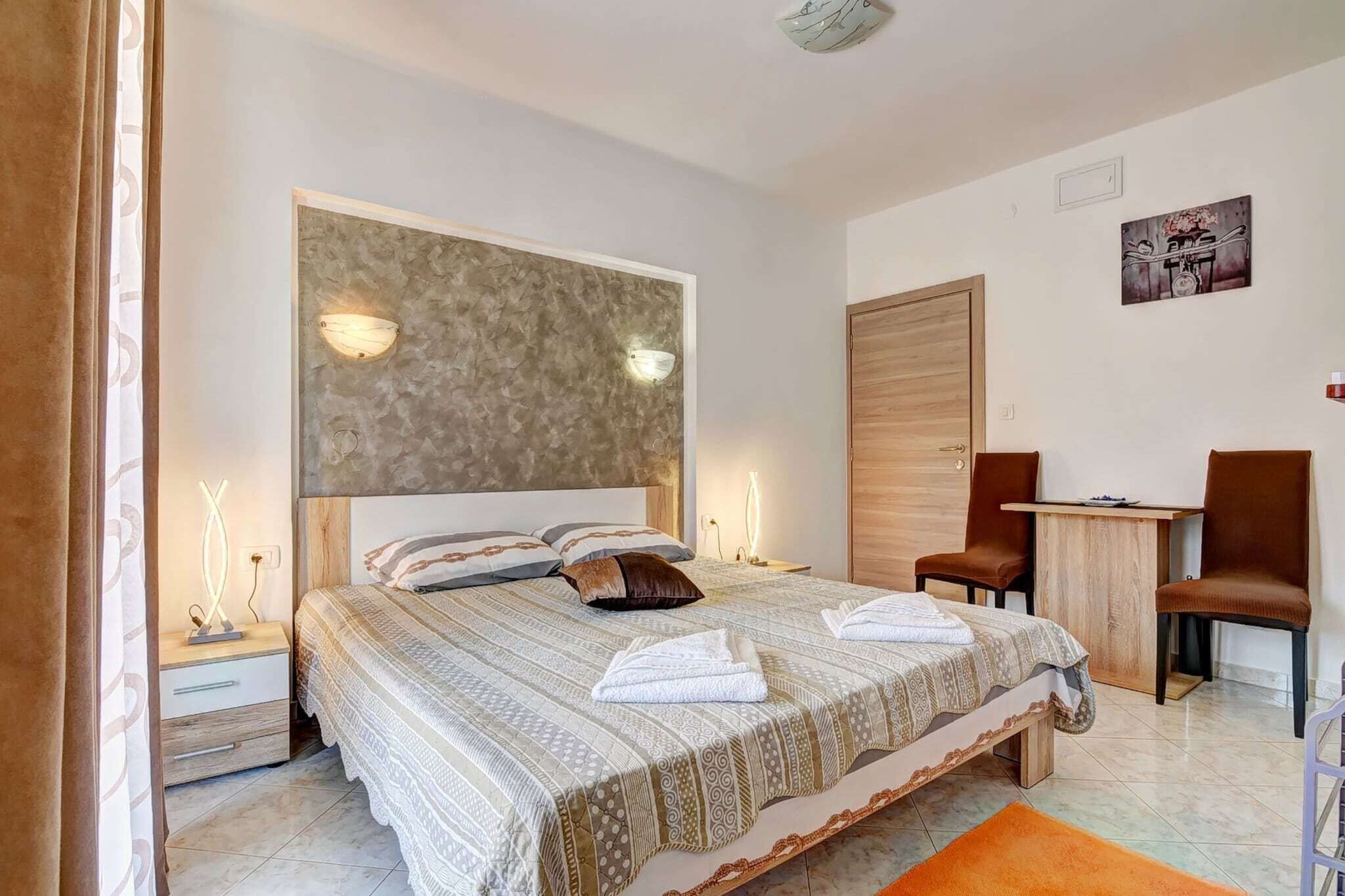 A modern bedroom with a large bed, bedside lamps, a desk, and a chair.