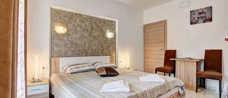 A modern bedroom with a large bed, bedside lamps, a desk, and a chair.