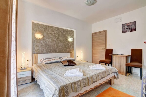 A modern bedroom with a large bed, bedside lamps, a desk, and a chair.