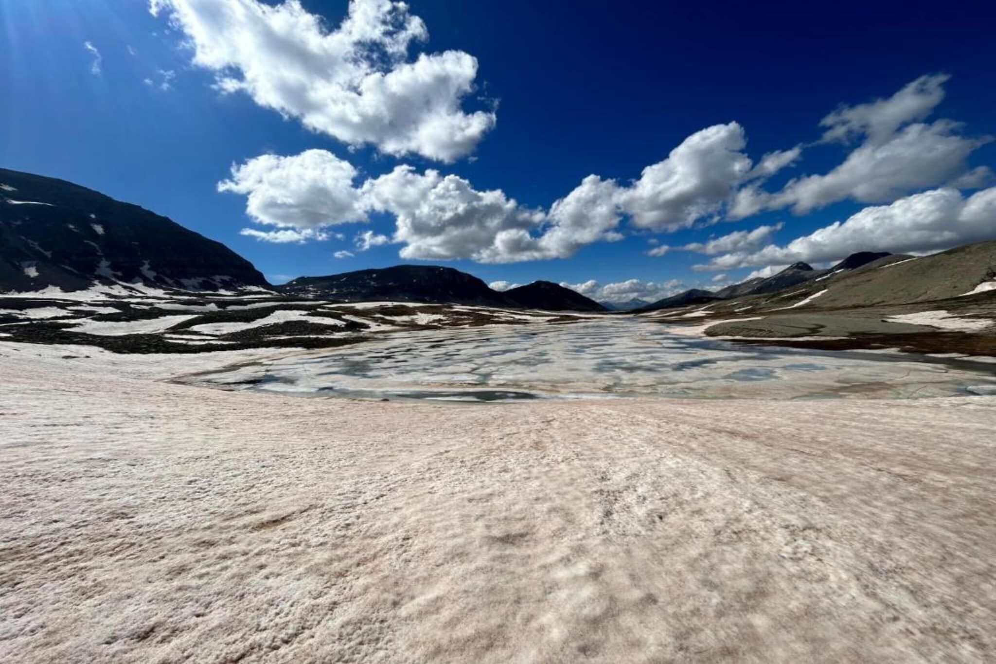 A vast, open landscape with snow-covered terrain and distant mountains under a clear sky.