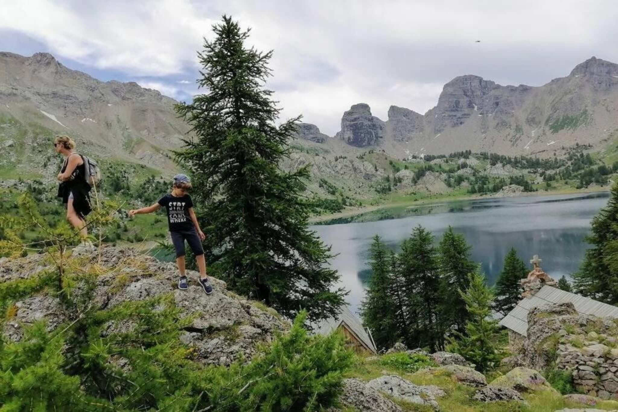 Un paysage montagneux avec un lac, un terrain rocheux et une petite cabane.