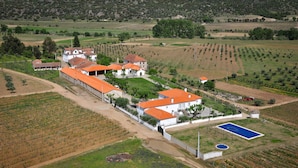 Vue aérienne d’une propriété comprenant plusieurs bâtiments, une piscine et des champs agricoles environnants.