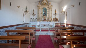 Ein Kircheninneres mit Holzbänken, einem roten Teppich und religiösen Statuen.