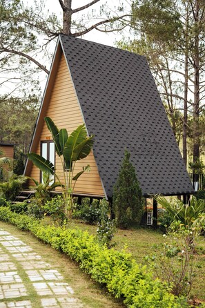 A triangular-shaped building with a sloped roof, surrounded by lush greenery and a stone pathway. - Phoenix Moc Chau Hotel (Moc Son)