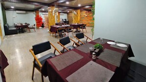 A conference room with multiple tables and chairs, air conditioning units, and a decorative wall. - Emerald Tree Moshi (Pune)