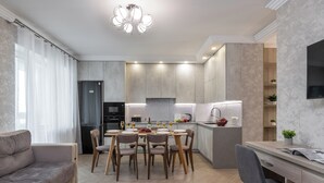 A modern kitchen with a dining area, featuring a central island, wooden chairs, and a built-in oven. - 3-room apt with view of National Library (Minsk)