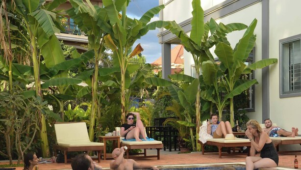 A pool area with lounge chairs and people relaxing. - Domnak Soksan Boutique (Siem Reap)