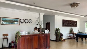 A reception area with a wooden desk, a pool table, and a large wall clock. - Domnak Soksan Boutique (Siem Reap)