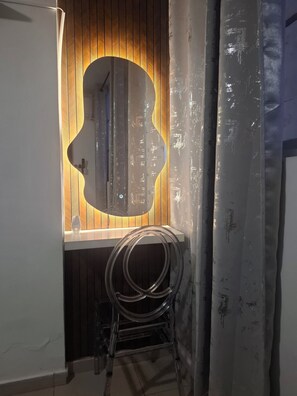 Una habitación con pared de paneles de madera, un espejo grande y un cable enrollado sobre un soporte.