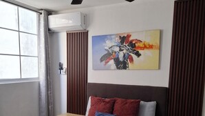 A modern hotel room with a bed, a ceiling fan, a painting, and a window with curtains.