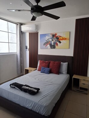 A modern hotel room with a bed, a ceiling fan, a painting, and a window with curtains.