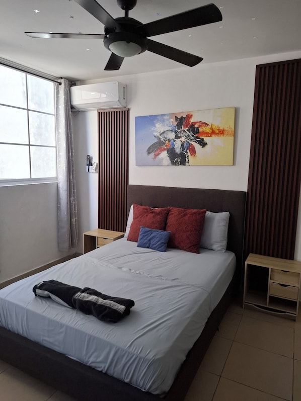 A modern hotel room with a bed, a ceiling fan, a painting, and a window with curtains.