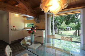 A modern kitchen with a glass dining table, white chairs, and a vase with flowers. - Casa Loft Pool, Garden, Treviso (Cendon)