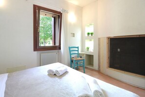 A bedroom with a bed, a window, a chair, and a radiator.