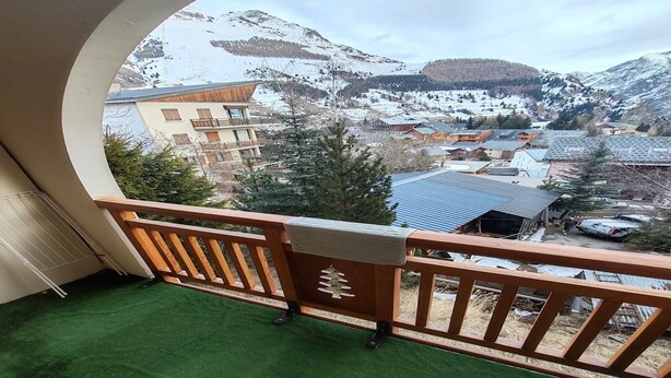 A balcony with a view of a snowy mountain landscape, a wooden railing, and a green artificial turf floor. - Studio in Les Deux Alpes near Ski Slopes (Les 2 Alpes)
