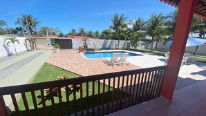A pool area with a wooden deck, two lounge chairs, and a small garden. - BSM Beach House - Top Leisure! (Barra Mar Barra de São Miguel)