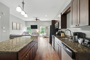 A modern kitchen with granite countertops, dark wooden cabinets, a built-in dishwasher, and a large island. - Bulldog Borough in Downtown Athens (Athens)