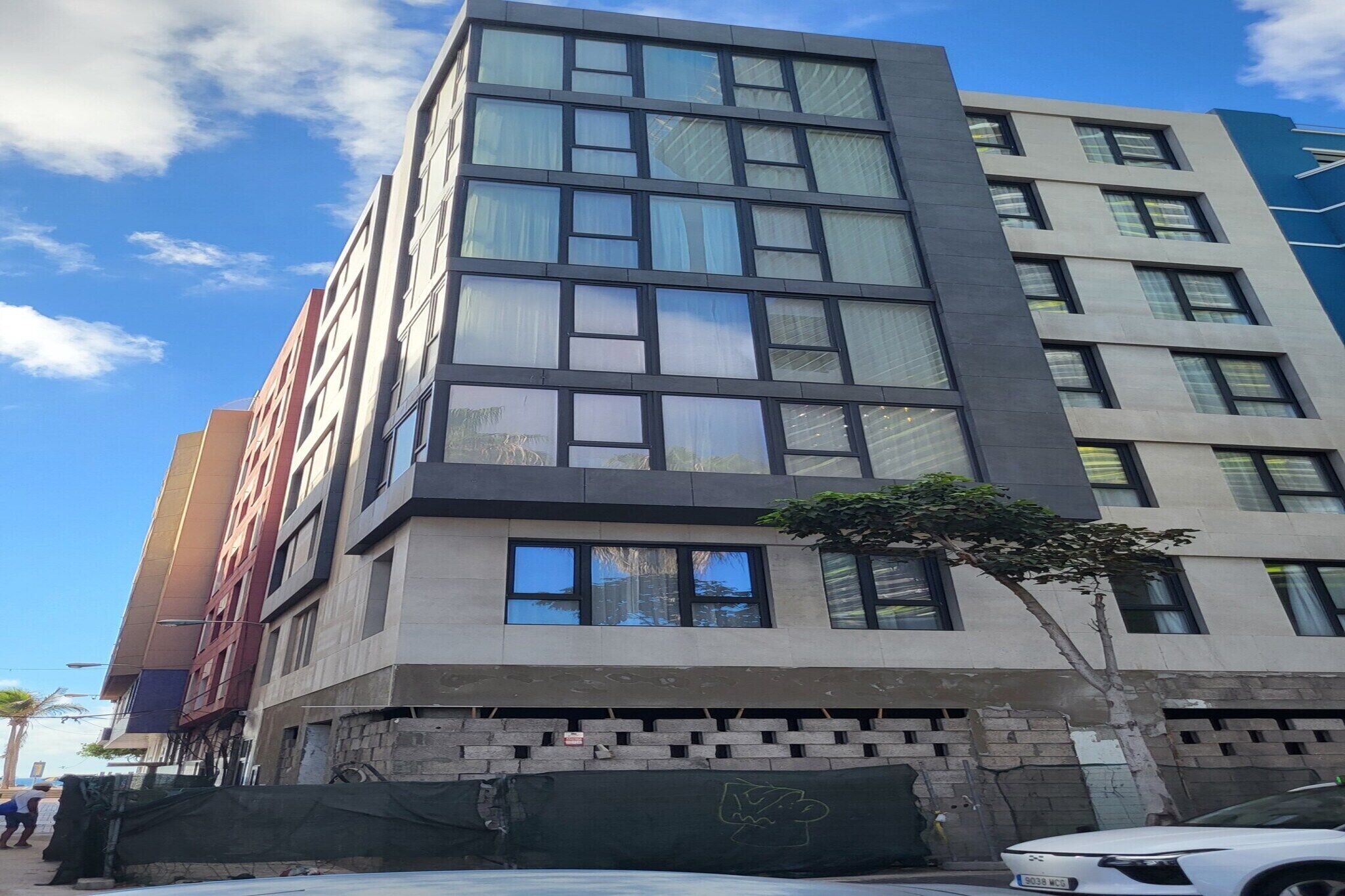 Un edificio de varios pisos con un diseño arquitectónico moderno, que combina fachadas de vidrio y hormigón.