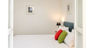 A neatly arranged bedroom with a bed, bedside lamp, and two framed pictures on the wall. - At Home Colosseo (Rome)