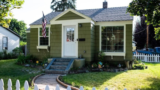 A single-story house with a front porch, a small front yard, and a white picket fence.